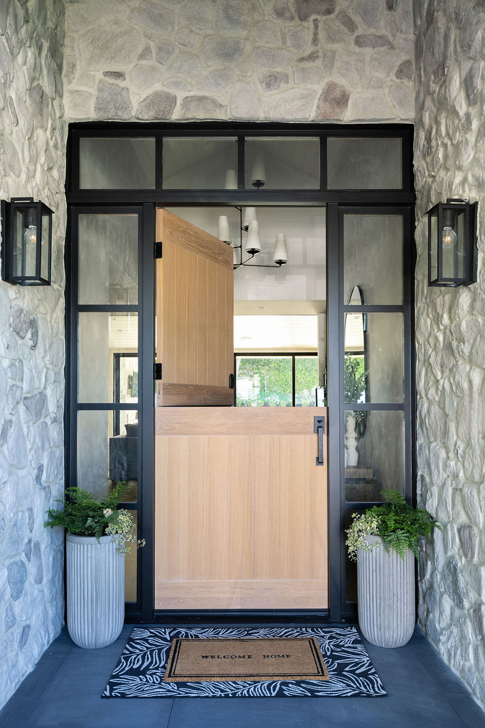 home entrance area with stone walls, black-framed windows and wood dutch door