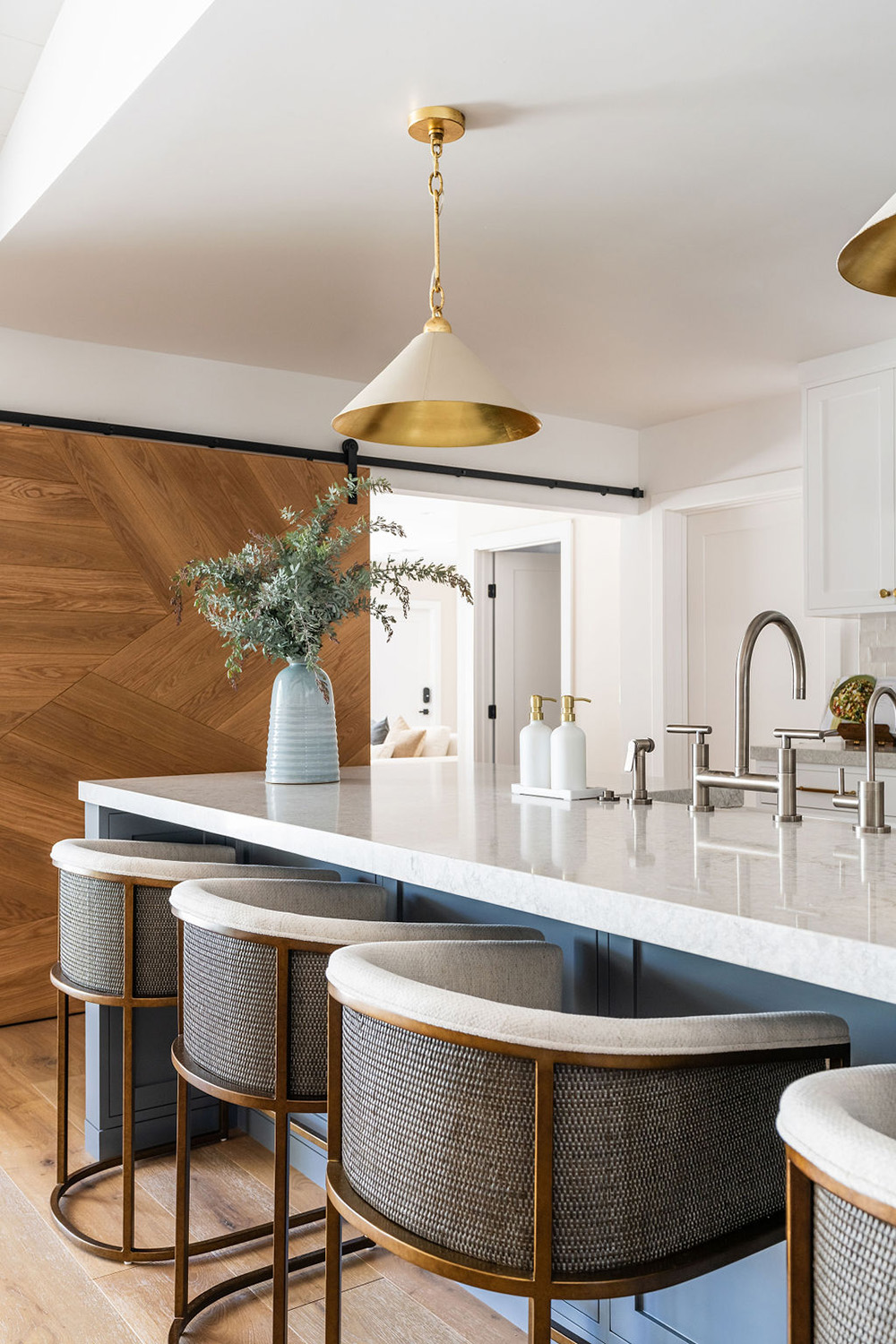 bright modern kitchen design with blue island, barrel style chairs and cone light fixtures