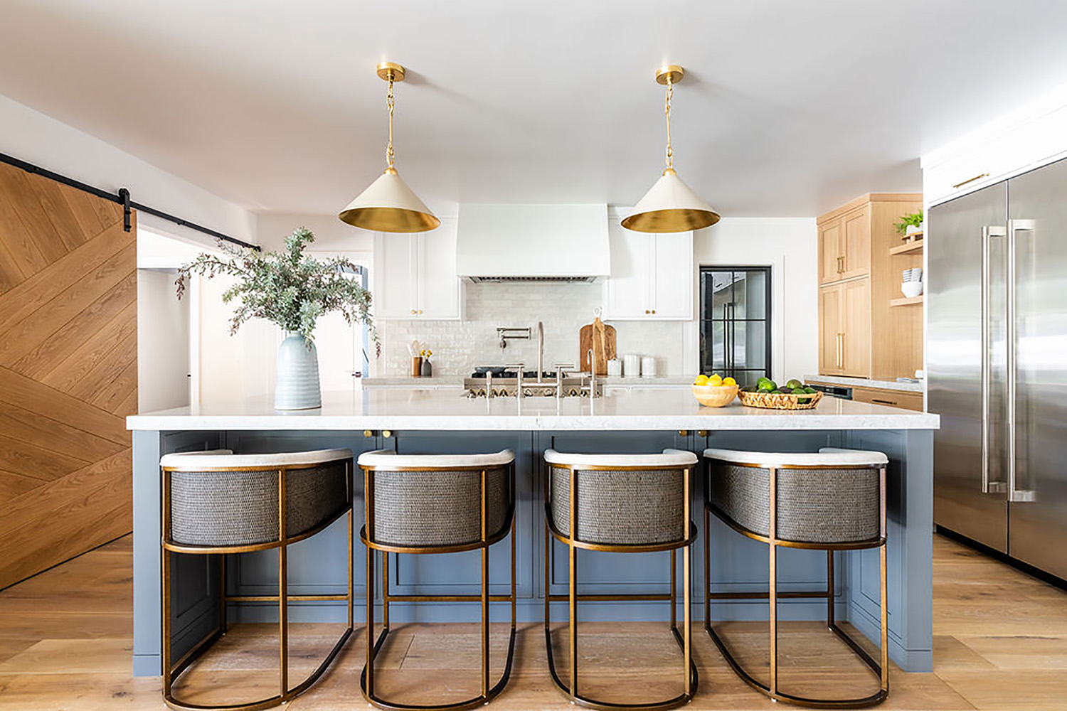 bright modern kitchen design with blue island, barrel style chairs and cone light fixtures