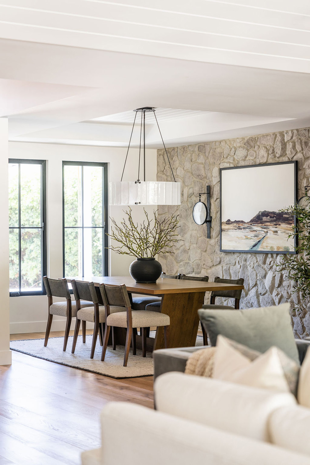 dining room area design with stone accent wall, large artwork and modern wood table