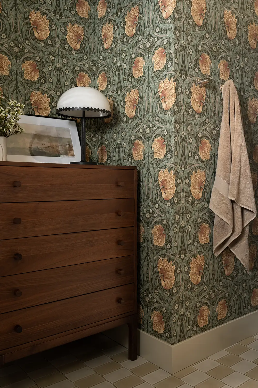 Interior design detail in the bathroom of a Tustin home featuring dark wood cabinet, floral wallpaper, and adorable lamp